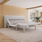 Ergomotion SmartSense gray adjustable bed with modern headboard in a stylish living room setting with wooden flooring and shelves.